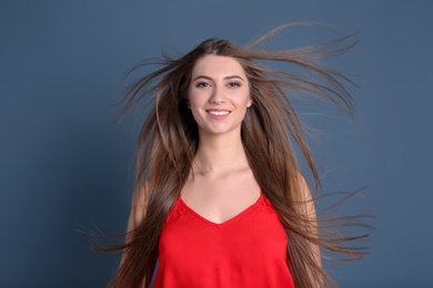 Portrait of young woman with long beautiful hair on color background