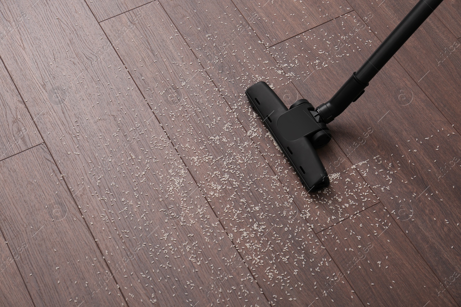 Photo of Vacuuming scattered rice from wooden floor. Space for text