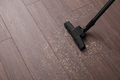 Photo of Vacuuming scattered rice from wooden floor. Space for text