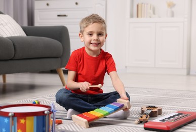 Photo of Little boy playing toy xylophone at home