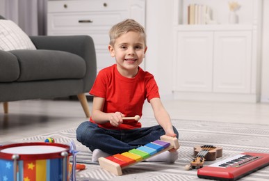 Little boy playing toy xylophone at home