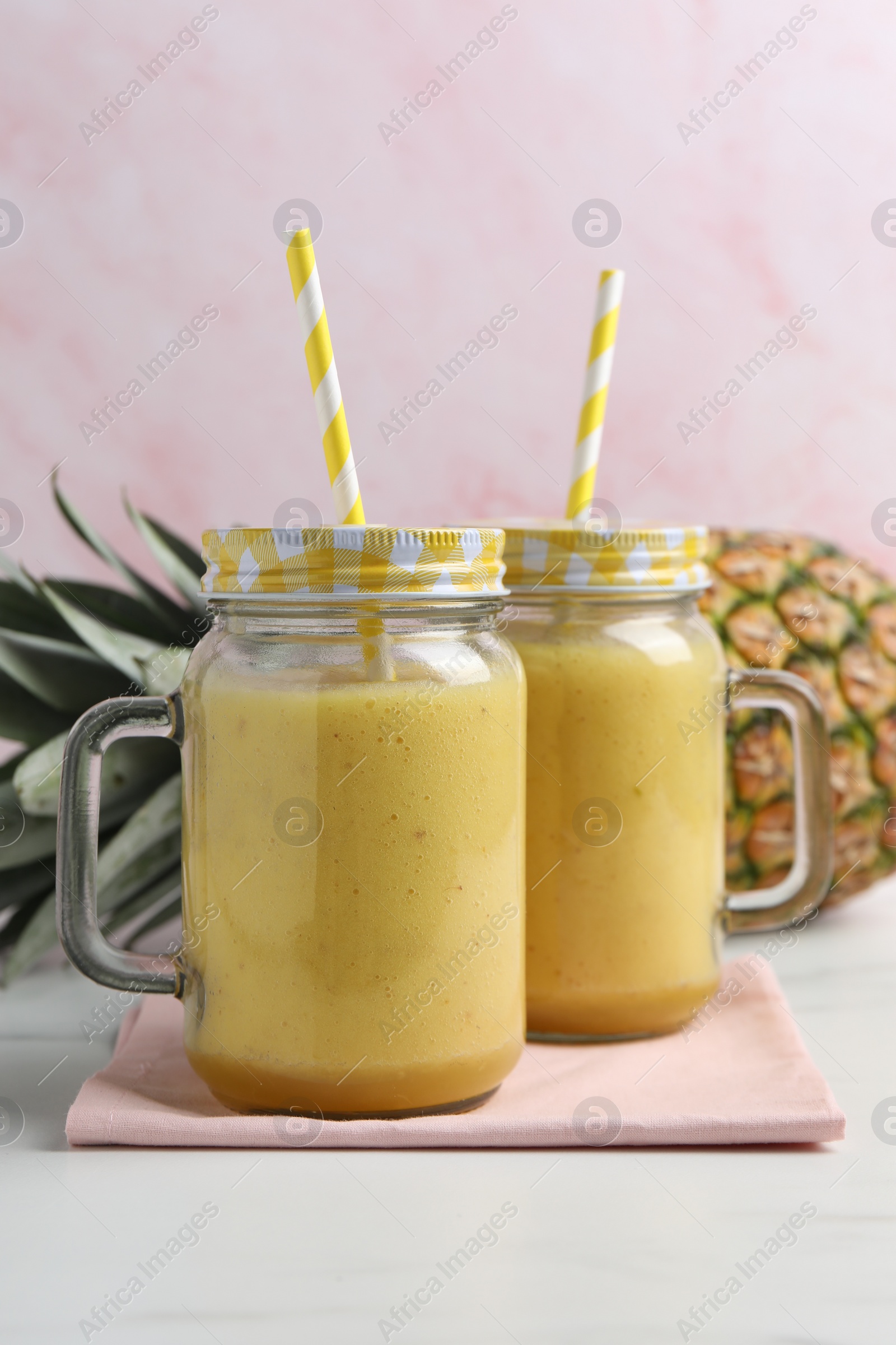 Photo of Tasty pineapple smoothie and fruit on white table