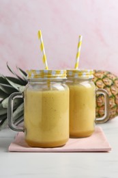 Photo of Tasty pineapple smoothie and fruit on white table