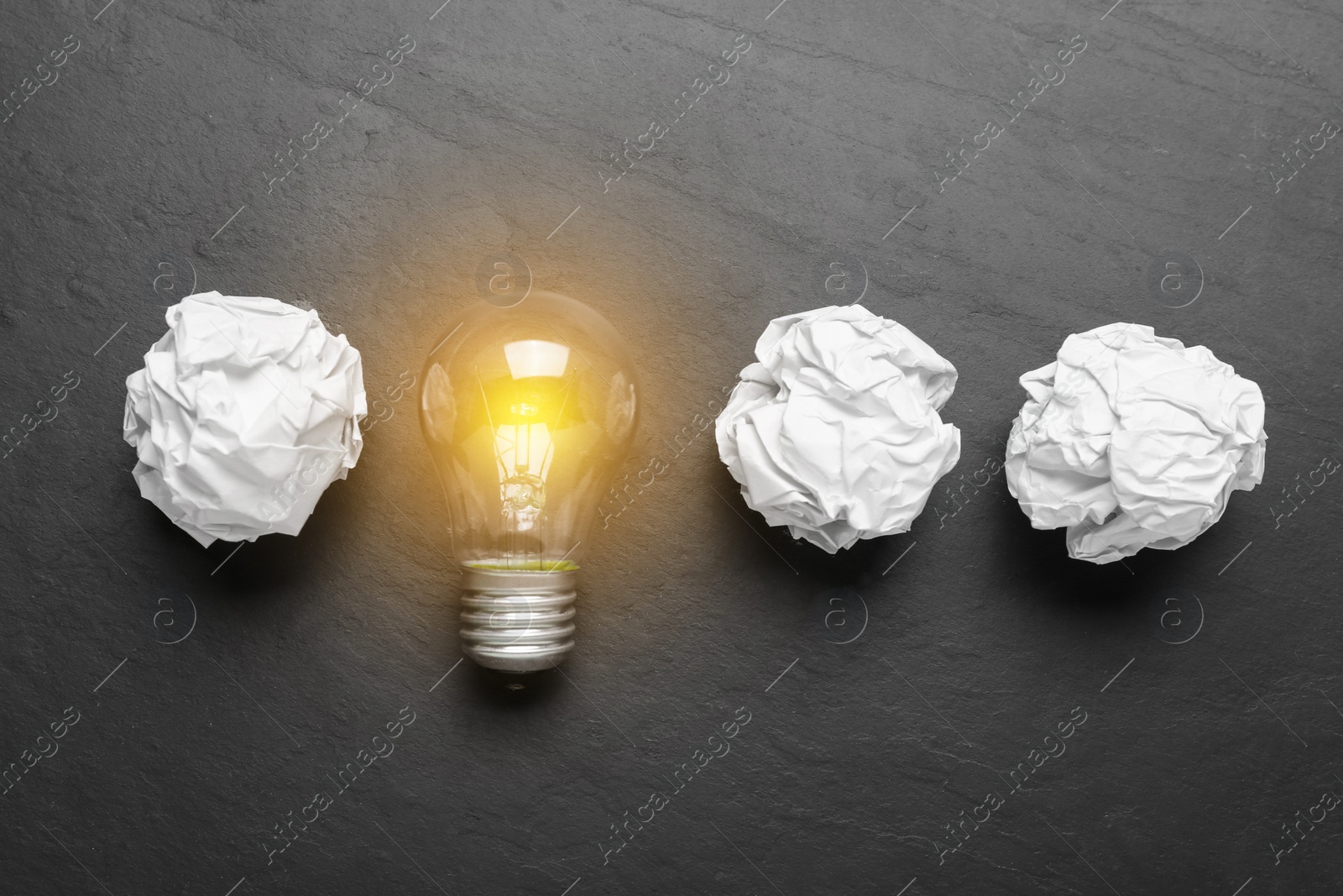 Photo of Creative flat lay composition with lightbulb and paper balls on black table. Idea concept