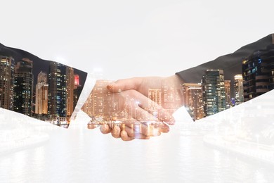 Image of Double exposure of cityscape and partners shaking hands on white background, closeup