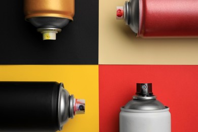 Cans of different graffiti spray paints on color background, flat lay