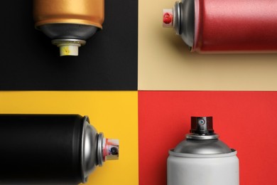 Photo of Cans of different graffiti spray paints on color background, flat lay