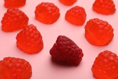 Photo of Delicious gummy candies and fresh raspberry on pink background, closeup