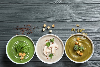 Various cream soups and space for text on wooden background, flat lay. Healthy food