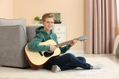 Photo of Teenage boy playing acoustic guitar in room