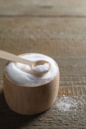 Photo of Organic salt in bowl and spoon on wooden table, closeup