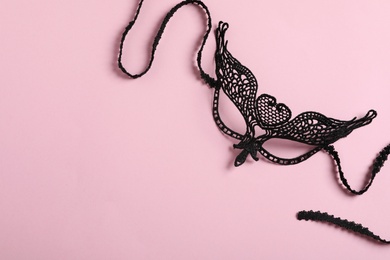 Photo of Black lace mask for sexual role play on pink background, top view with space for text