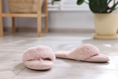 Photo of Pink soft slippers on light wooden floor at home, closeup