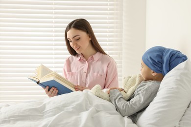 Photo of Childhood cancer. Mother reading book to daughter in hospital