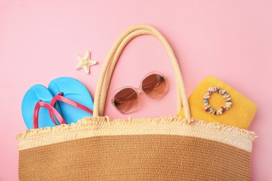 Photo of Bag with beach accessories on pink background, flat lay