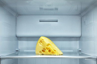 Photo of Piece of cheese on shelf in refrigerator