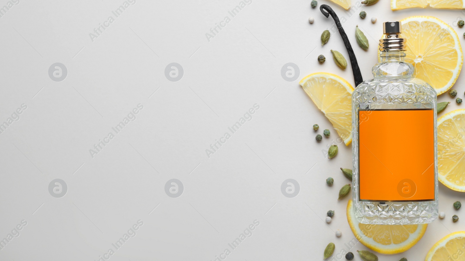Photo of Bottle of perfume, lemon slices and cardamom on light grey background, top view. Space for text
