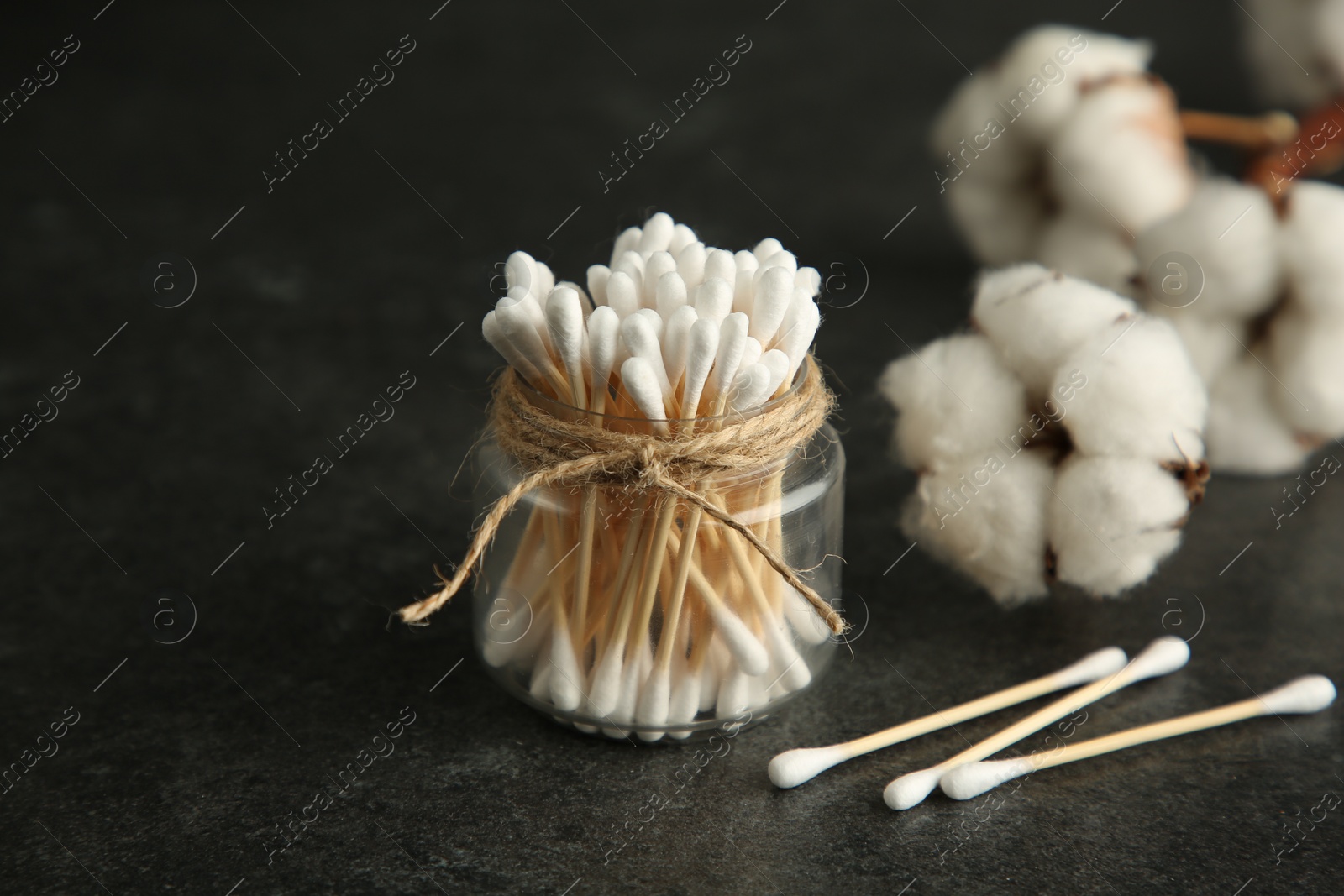 Photo of Cotton swabs and flowers on black table, closeup