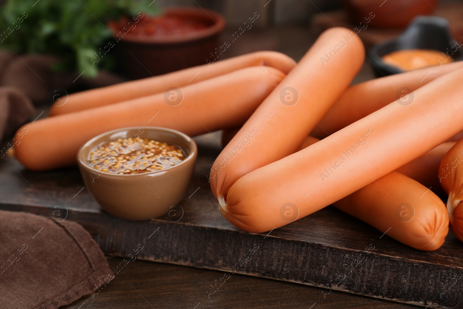 Photo of Delicious sausages and mustard on wooden table, closeup