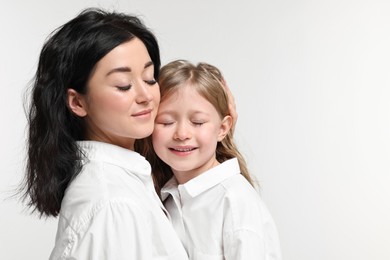 Beautiful mother with little daughter on white background. Space for text