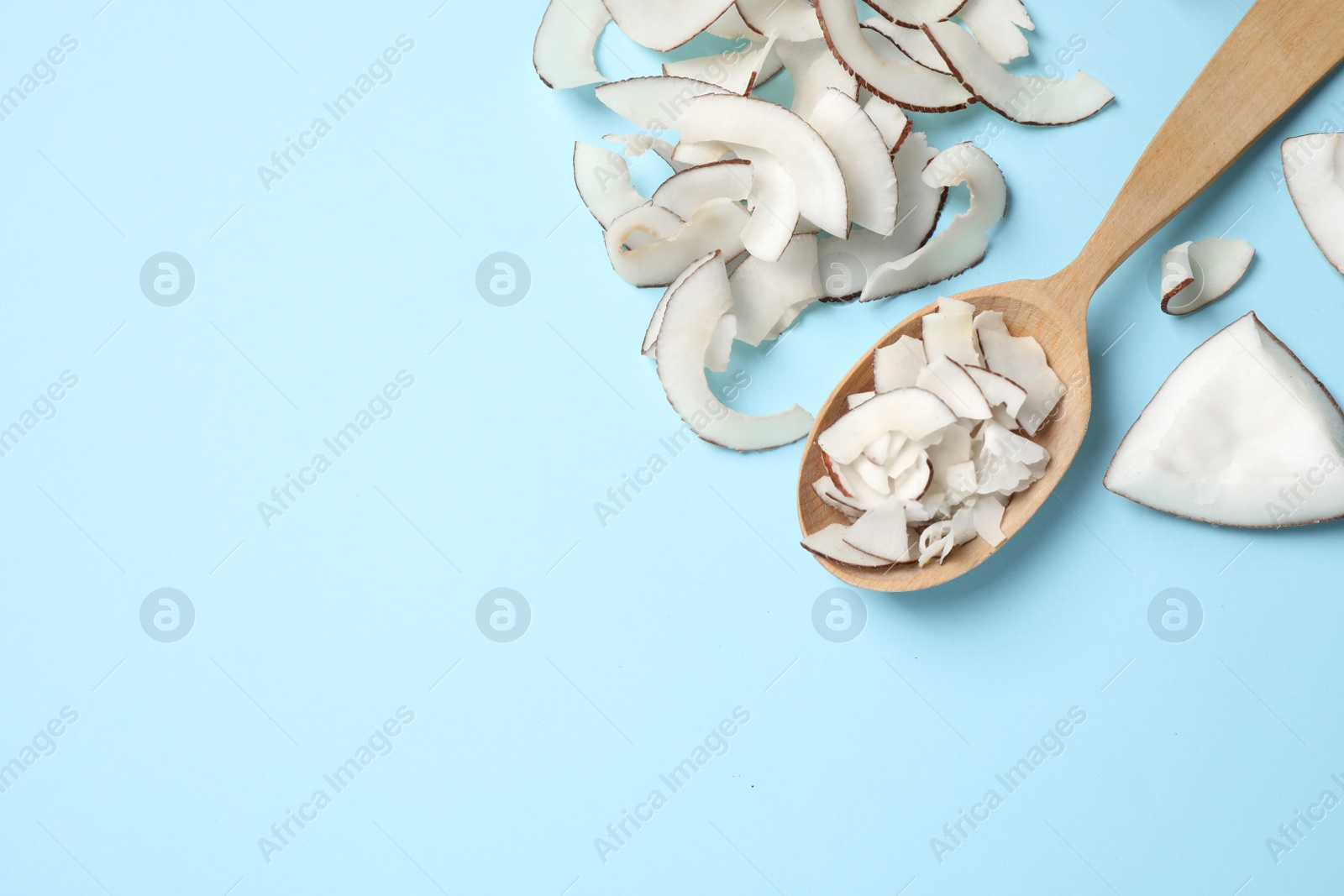 Photo of Flat lay composition with tasty coconut chips on light blue background. Space for text