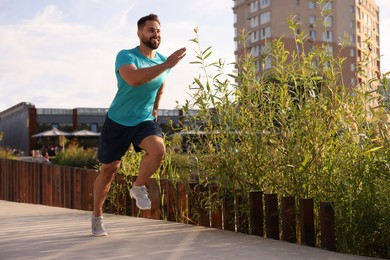 Smiling man running outdoors on sunny day. Space for text