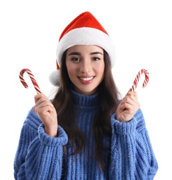 Beautiful woman in Santa Claus hat holding candy canes on white background