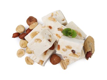 Photo of Pieces of delicious nougat, nuts and mint on white background, top view