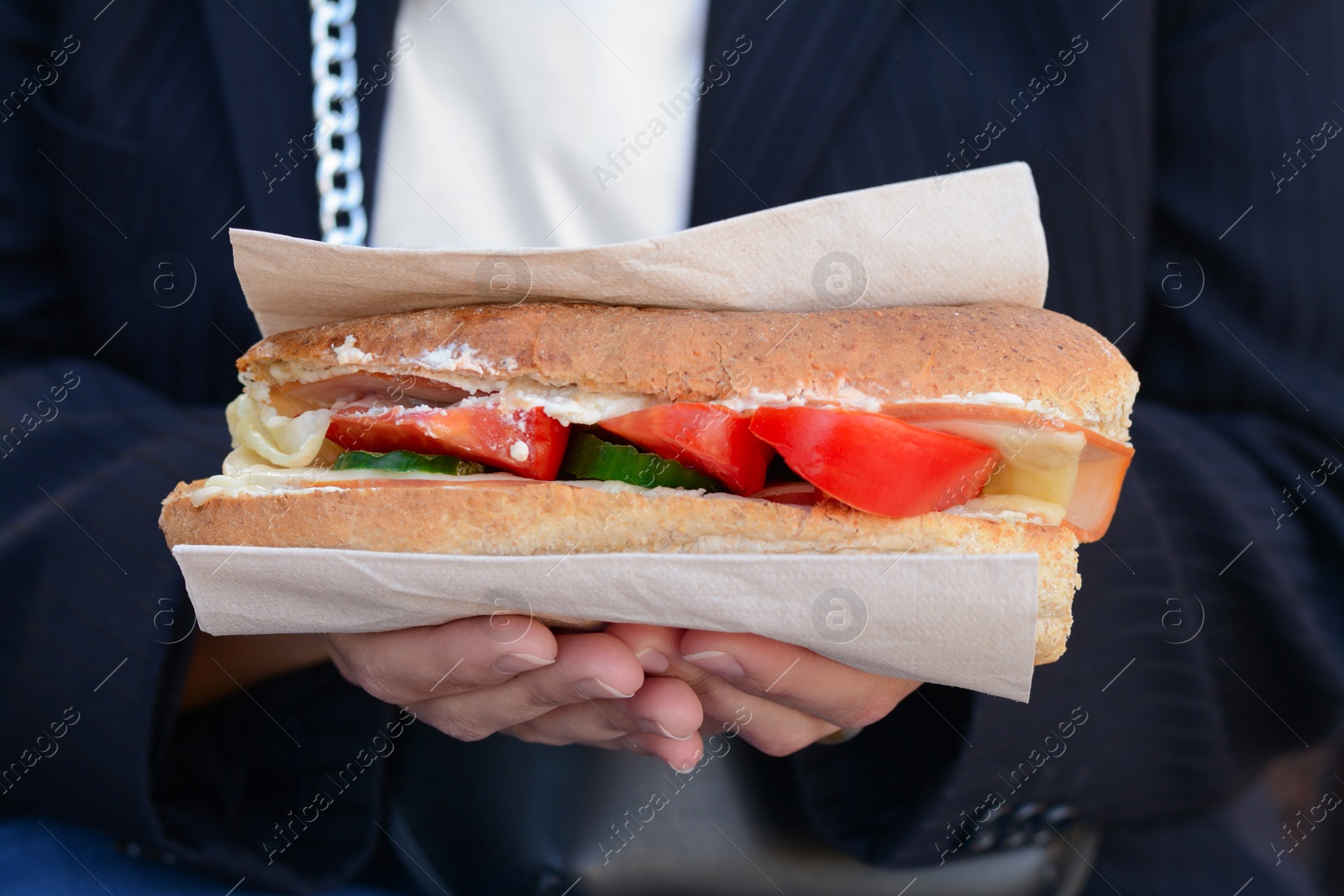 Photo of Woman holding tasty sandwich with vegetables outdoors, closeup. Street food