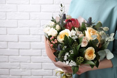 Photo of Woman with bouquet of beautiful roses near white brick wall, closeup