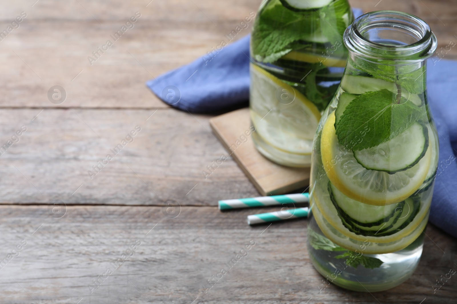 Photo of Refreshing water with cucumber, lemon and mint on wooden table. Space for text