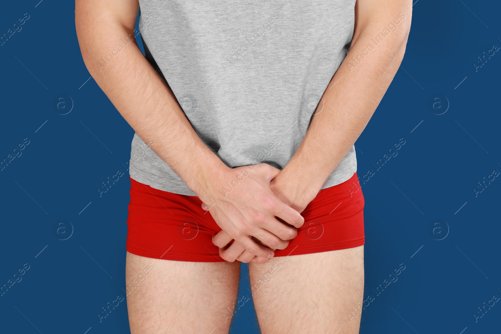 Photo of Man suffering from pain on blue background, closeup. Urology problems