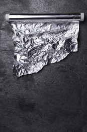 Photo of Roll of aluminum foil on grey table, top view. Space for text