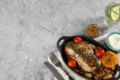 Photo of Tasty chicken, vegetables, drink with tarragon and salad dressings served on grey table, flat lay. Space for text
