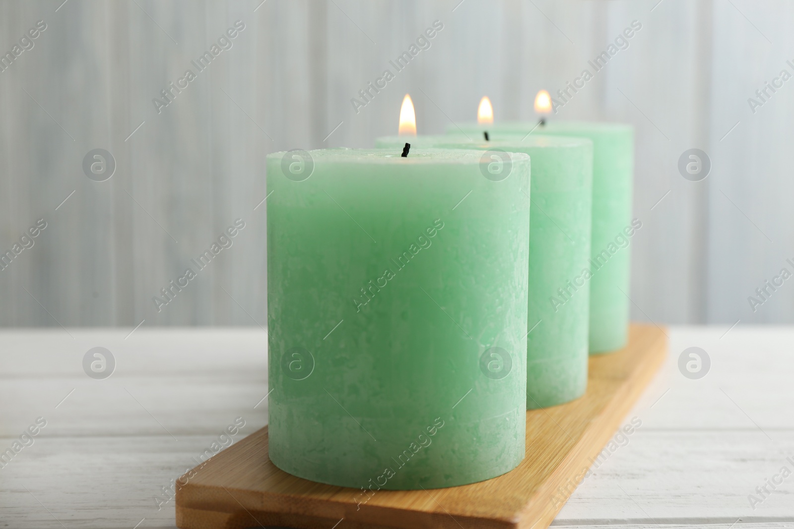 Photo of Bamboo plate with three burning candles on table