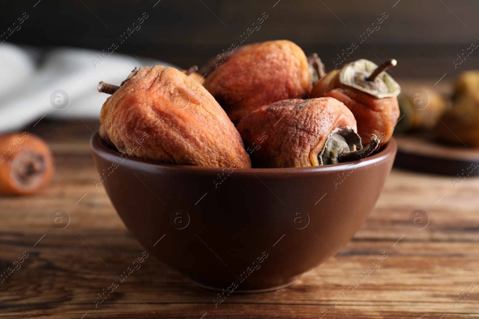 Photo of Tasty dried persimmon fruits in bowl on wooden table