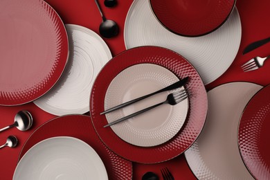 Stylish table setting with cutlery on red background, flat lay