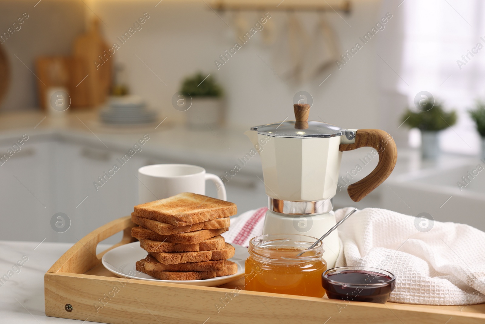 Photo of Breakfast served in kitchen. Tray with toasts, honey, jam and coffee on white table