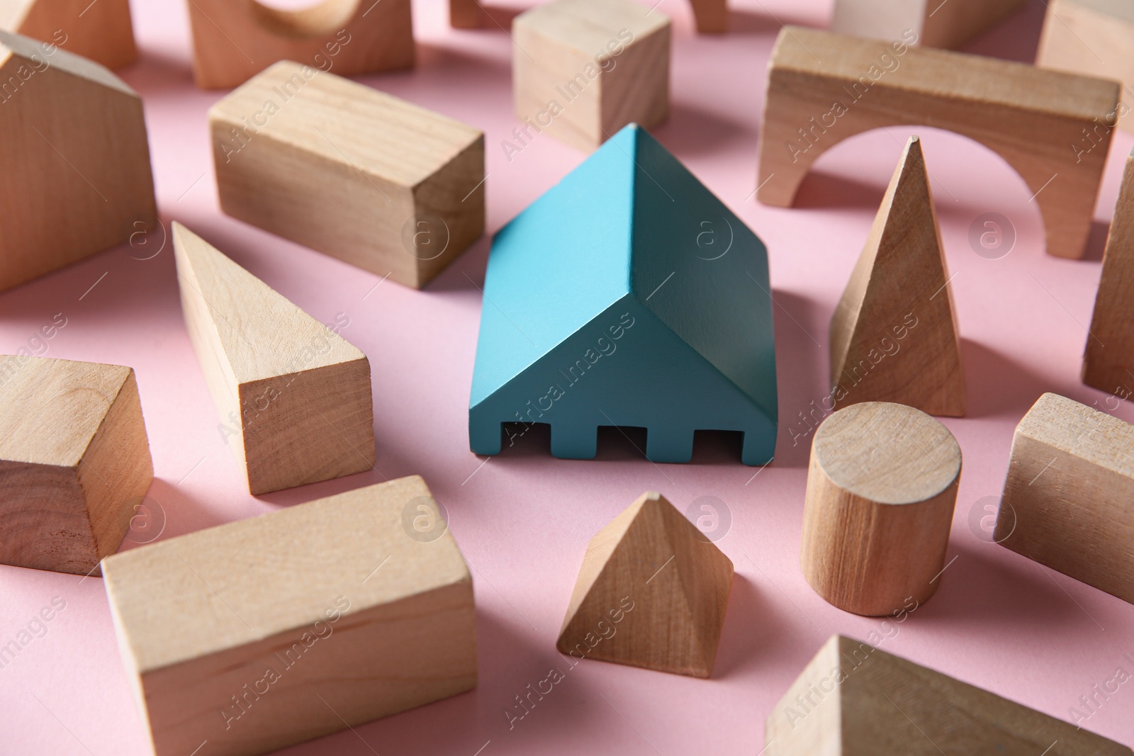 Photo of One turquoise toy building block among others on pink background. Diversity concept