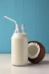 Photo of Glass bottle of delicious vegan milk and coconut on white marble table