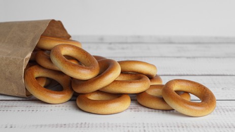 Photo of Bag with tasty dry bagels (sushki) on white wooden table, closeup