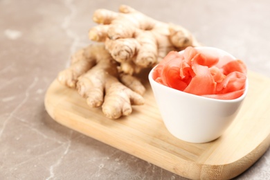 Photo of Spicy pickled ginger and root on grey table. Space for text