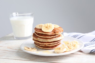 Plate of banana pancakes with honey on white wooden table