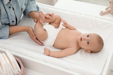 Photo of Mother changing her baby's diaper on table at home