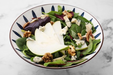 Delicious pear salad in bowl on white marble table, closeup