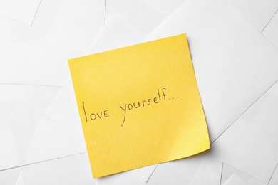 Photo of Note with words LOVE YOURSELF on paper sheets, top view