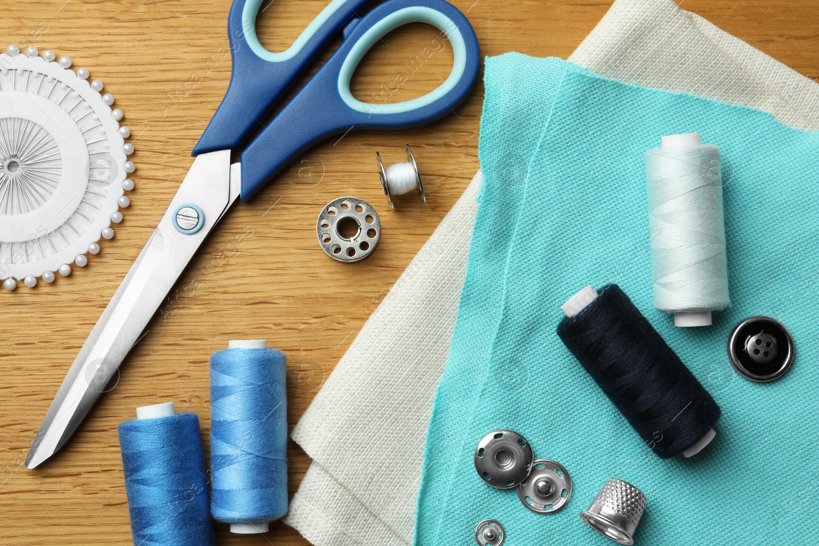 Photo of Flat lay composition with spools of threads and sewing tools on wooden table