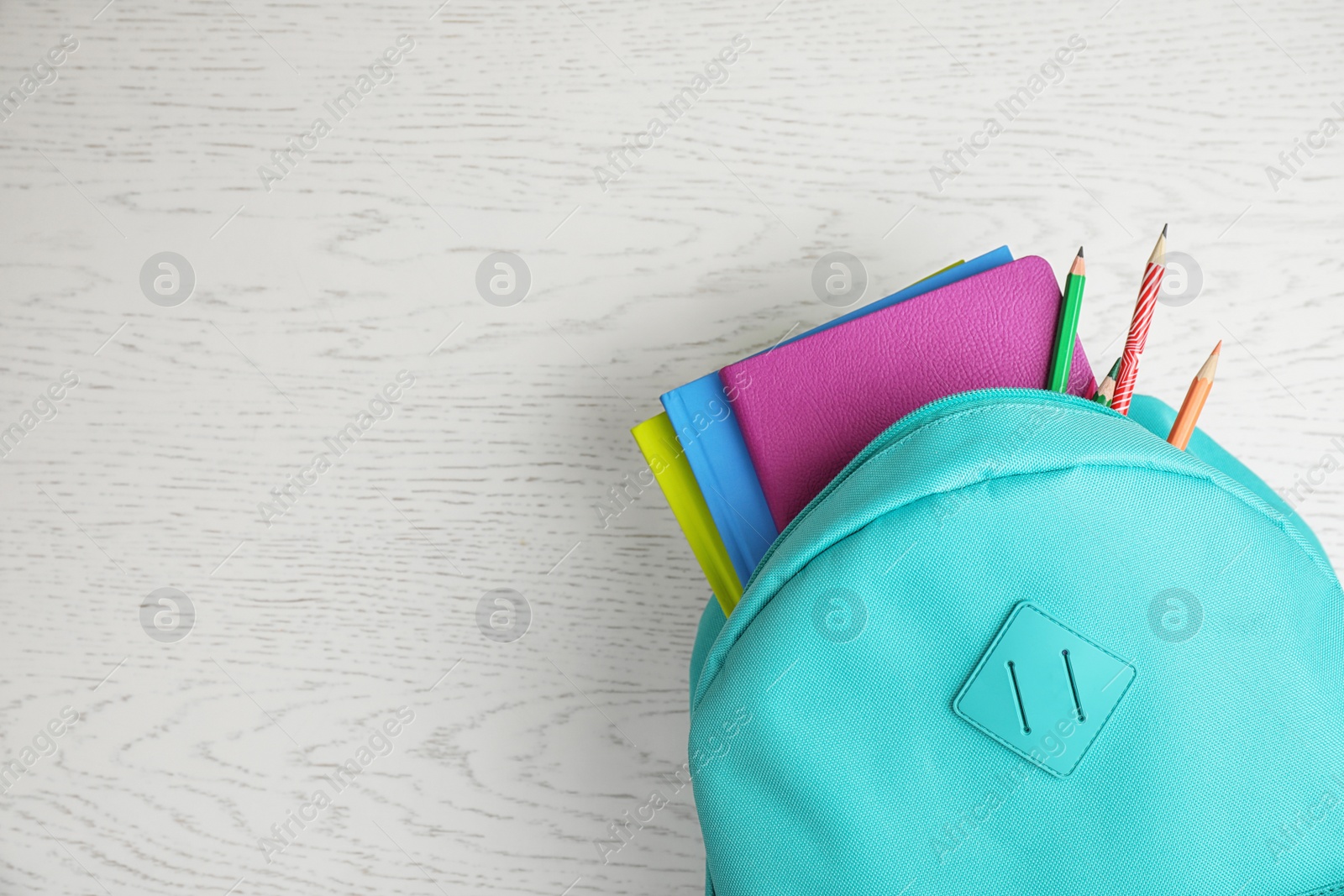 Photo of Stylish backpack with different school stationary on white wooden table, top view. Space for text