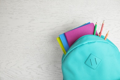 Photo of Stylish backpack with different school stationary on white wooden table, top view. Space for text