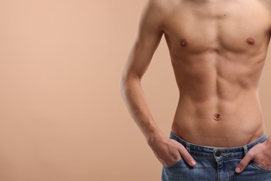 Shirtless man with slim body on beige background, closeup. Space for text